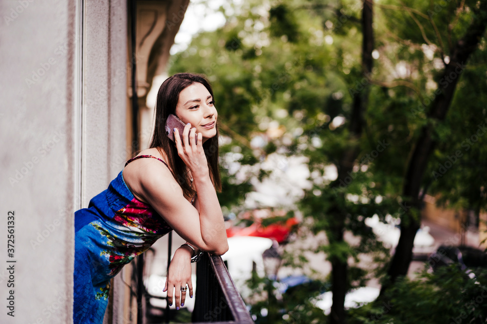 Woman talking through phone while leaning on balcony railing Woman talking through phone while leaning on balcony railing