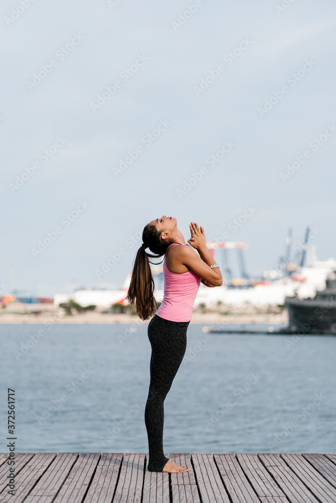 Female athlete with eyes closed meditating while standing on pier against sea Female athlete with eyes closed meditating while standing on pier against sea