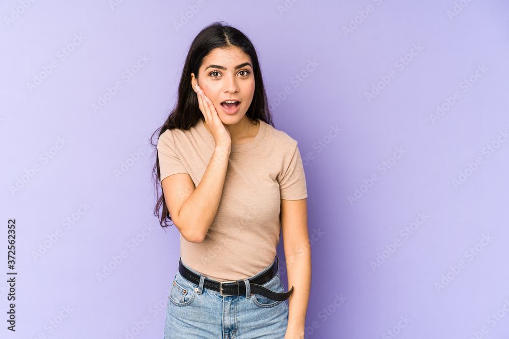 Young indian woman isolated on purple background shouts loud, keeps eyes opened and hands tense. Young indian woman isolated on purple background shouts loud, keeps eyes opened and hands tense.