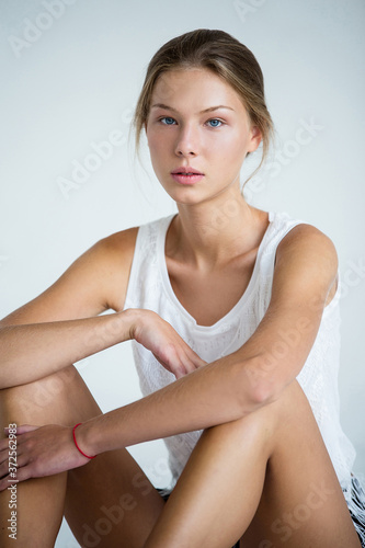 young beautiful woman with tanned skin sits on  light floor,