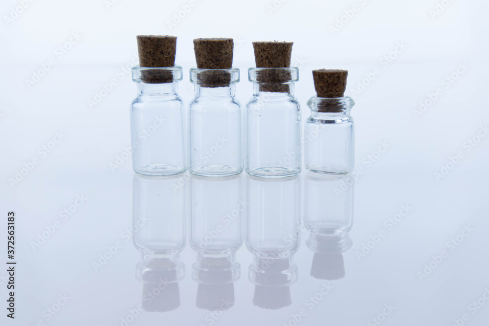 Empty small glass transparent flask bottles sealed with wooden stoppers. Objects are reflected on the surface as in a mirror. Macro Empty small glass transparent flask bottles sealed with wooden stoppers. Objects are reflected on the surface as in a mirror. Macro