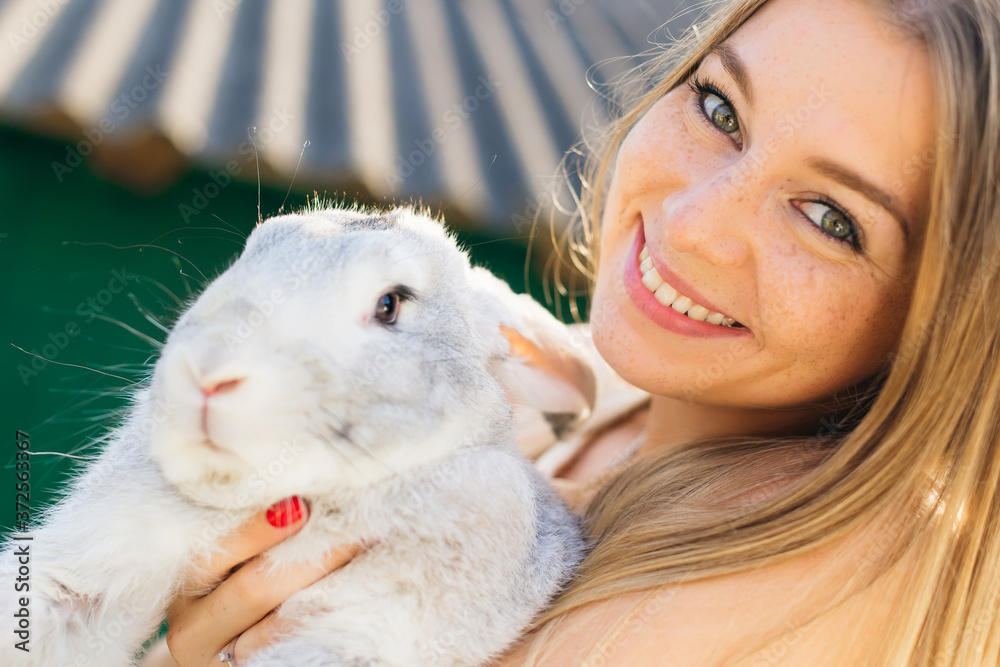 Lovely woman hold white rabbit. Portrait of young woman posing w Lovely woman hold white rabbit. Portrait of young woman posing w