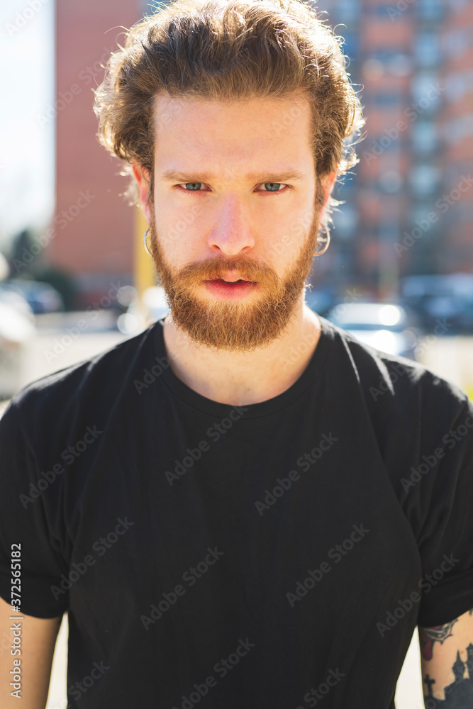Close-up of bearded handsome man standing in city during sunny day Close-up of bearded handsome man standing in city during sunny day