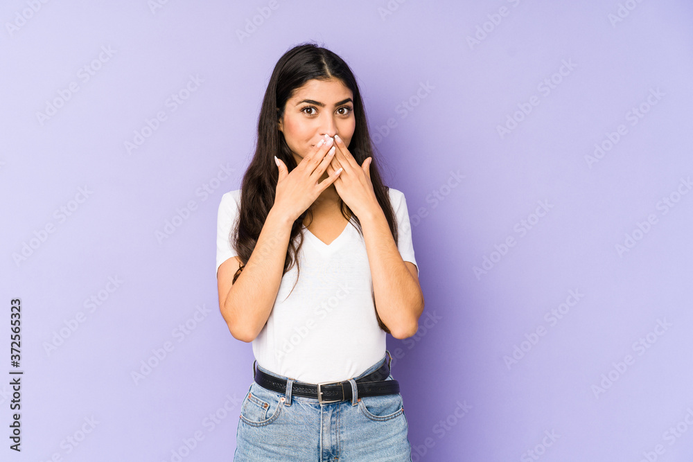 Young indian woman isolated on purple background shocked covering mouth with hands. Young indian woman isolated on purple background shocked covering mouth with hands.