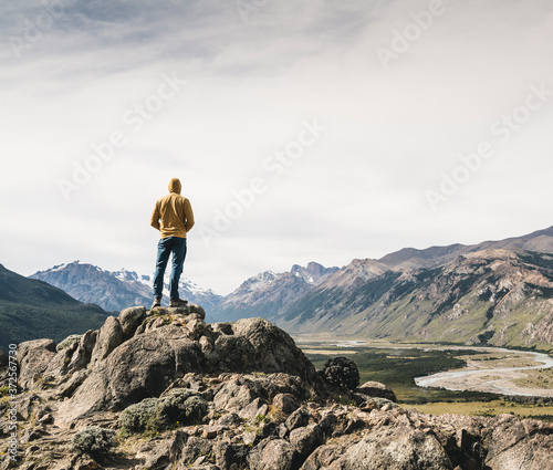 Mature man wearing hood looking at mountains against sky while standing on rock  Patagonia  Argentina