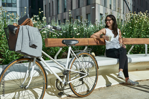 Thoughtful female commuter sitting on bench in city during sunny day