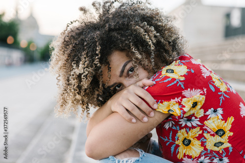 Confident young woman hugging knees while sitting on steps during sunny day