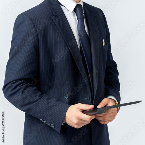 Portrait of a businessman in a blue suit holding an electronic tablet on a white background. No face visible.