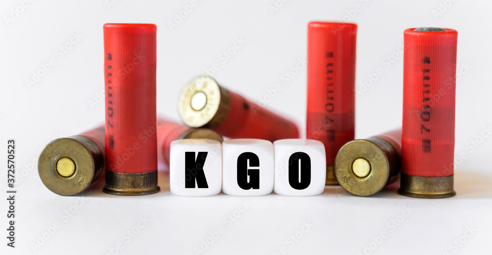 Against the background of rifle cartridges, there are white cubes with text KGO. Against the background of rifle cartridges, there are white cubes with text KGO.