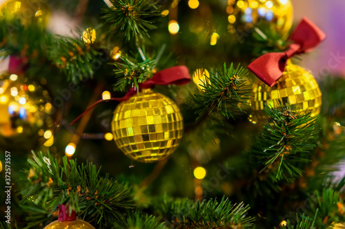 Christmas tree with decorations, shiny golden balls, illumination light garlands. Abstract festive background for design. Selective focus.