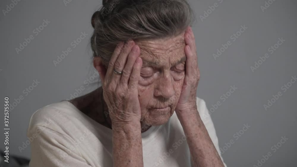 Senior woman with headache at home. Old grandmother with wrinkles and gray hair holding her head high blood pressure and migraine asks for help. Health care concept. Having painful feelings migraine Senior woman with headache at home. Old grandmother with wrinkles and gray hair holding her head high blood pressure and migraine asks for help. Health care concept. Having painful feelings migraine