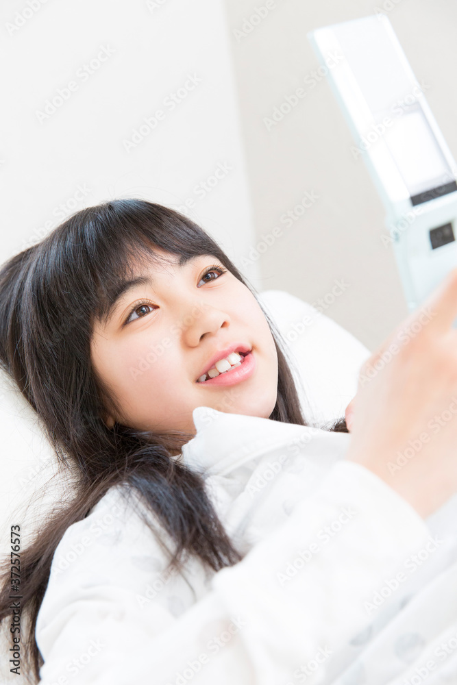 寝転んで携帯メールを見る女の子 寝転んで携帯メールを見る女の子
