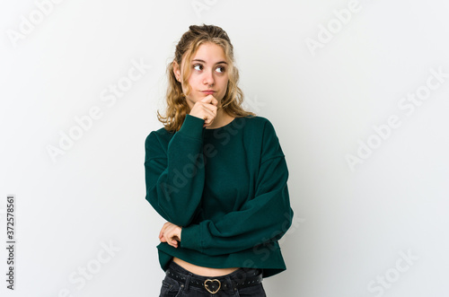 Young caucasian woman on white backrgound looking sideways with doubtful and skeptical expression. photo