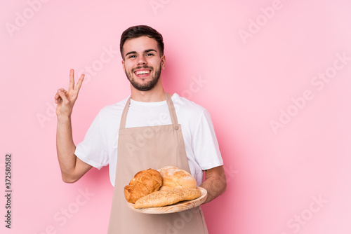 Young caucasian baker man isolated joyful and carefree showing a peace symbol with fingers.