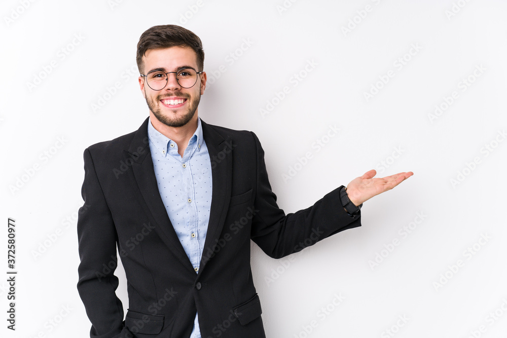 Young caucasian business man posing in a white background isolated Young caucasian business man showing a copy space on a palm and holding another hand on waist. Young caucasian business man posing in a white background isolated Young caucasian business man showing a copy space on a palm and holding another hand on waist.