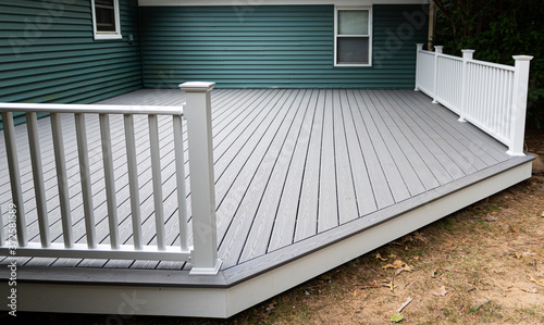 New composite deck on the back of a house with green vinyl siding. photo