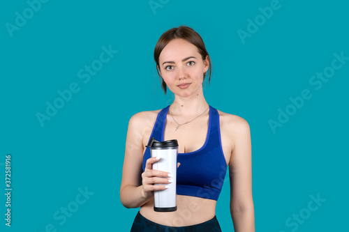 Girl in sports uniform with a cup of water on a blue background © vell