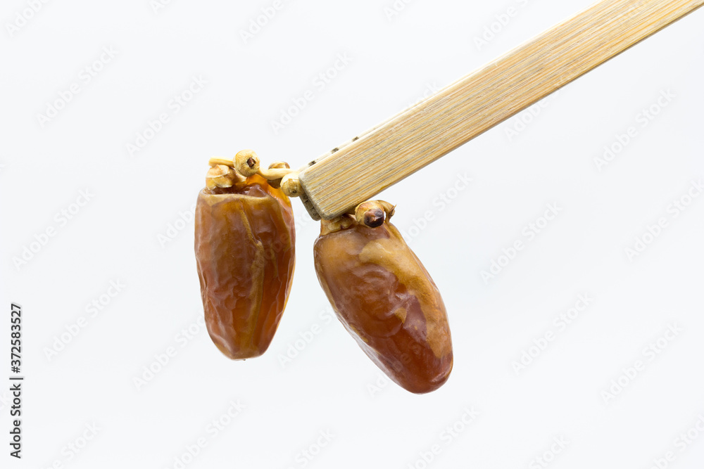 dátiles desecados en rama sujetos con pinza de bambú sobre fondo blanco ...
