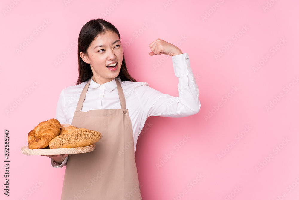 Young chinese baker woman isolated raising fist after a victory, winner concept.