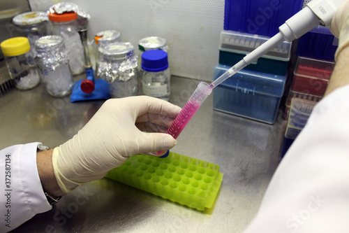 Close up of scientist manipulating a pipette and test tube in a laboratory work bench.