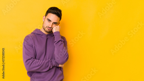 Young caucasian man isolated on yellow bakground who feels sad and pensive, looking at copy space.