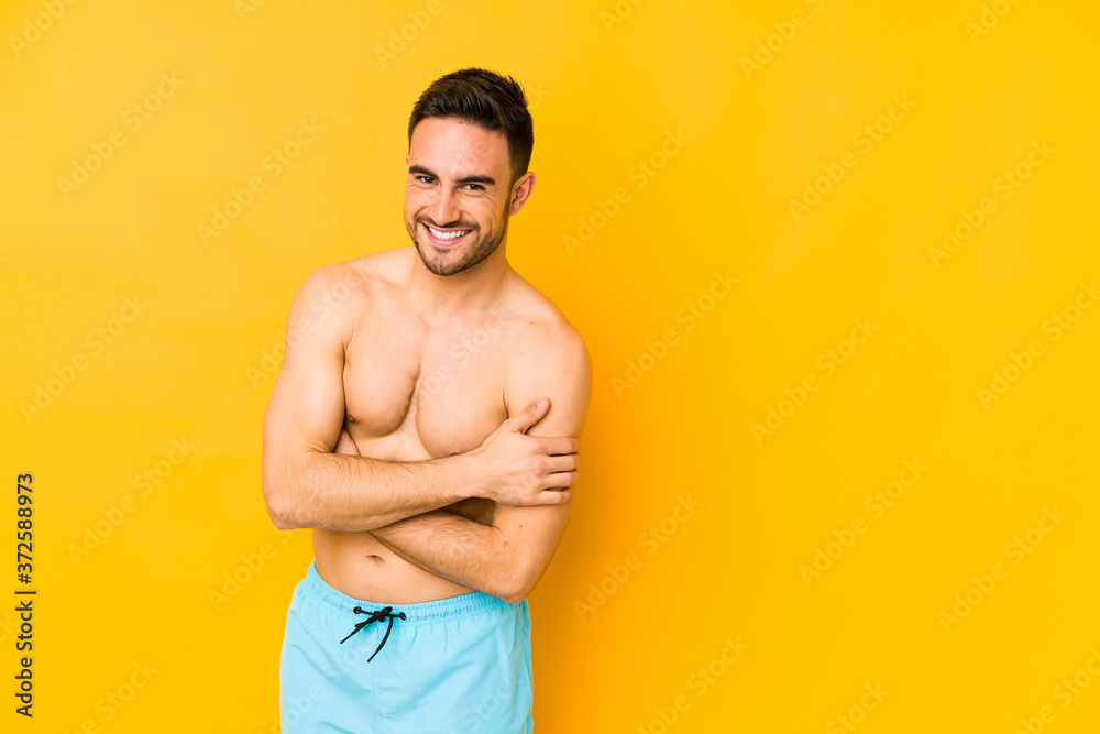 Young caucasian man with swimsuit isolated on yellow background Young caucasian man with trlaughing and having fun.