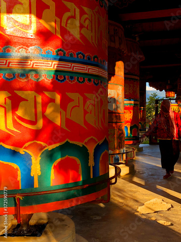 An Elderly Woman Spins a Large Prayer Wheel at Kyichu Lhakhang Temple in Paro Valley, Bhutan