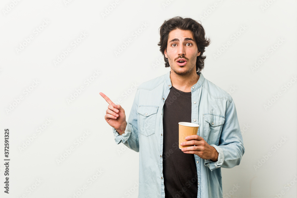 Young cool man drinking a coffee pointing to the side Young cool man drinking a coffee pointing to the side