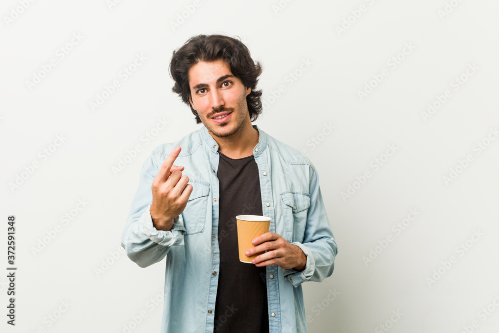 Young cool man drinking a coffee pointing with finger at you as if inviting come closer. Young cool man drinking a coffee pointing with finger at you as if inviting come closer.