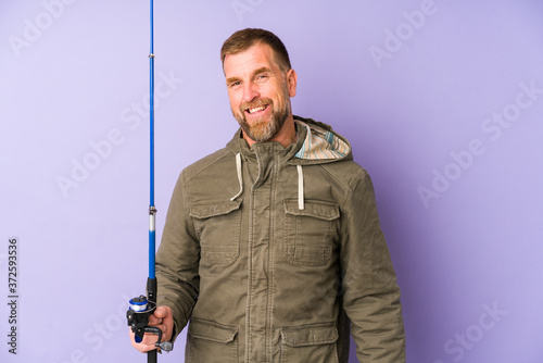 Senior fisherman isolated on purple background happy, smiling and cheerful.