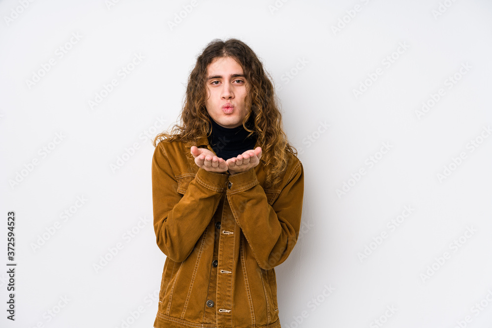 Long hair man posing isolated folding lips and holding palms to send air kiss. Long hair man posing isolated folding lips and holding palms to send air kiss.