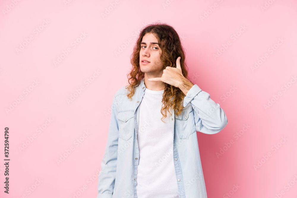 Long hair man posing isolated showing a mobile phone call gesture with fingers. Long hair man posing isolated showing a mobile phone call gesture with fingers.