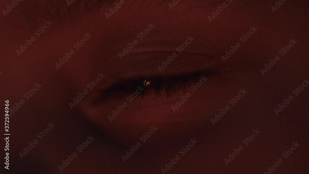 Static close up FHD shot of a human eye in a flickering firelight in