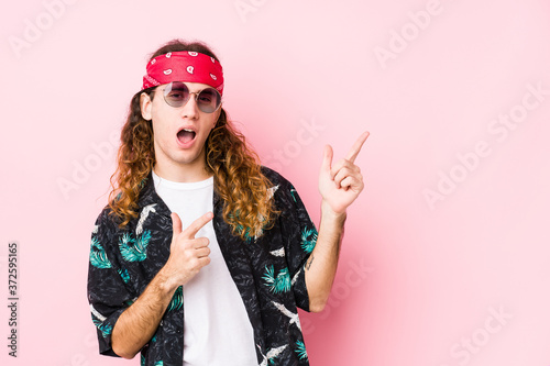 Young hippie caucasian man isolated pointing with forefingers to a copy space, expressing excitement and desire.