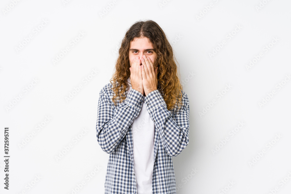 Young long hair man posing isolated laughing about something, covering mouth with hands. Young long hair man posing isolated laughing about something, covering mouth with hands.