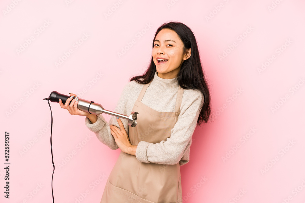 Young chinese woman holding a mixer isolated showing a dislike gesture, thumbs down. Disagreement concept. Young chinese woman holding a mixer isolated showing a dislike gesture, thumbs down. Disagreement concept.
