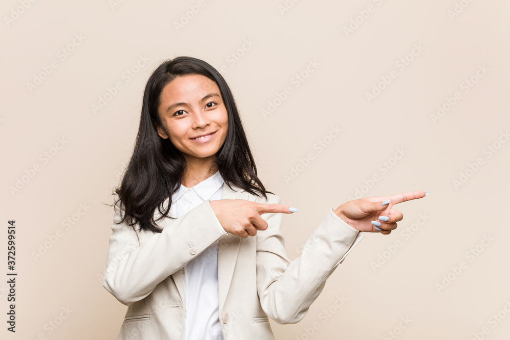 Young business chinese woman excited pointing with forefingers away. Young business chinese woman excited pointing with forefingers away.