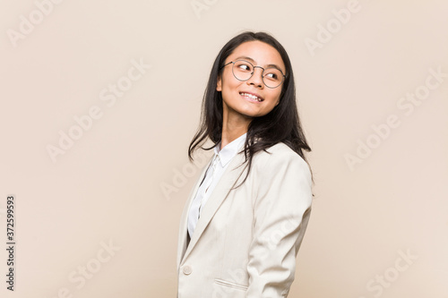 Young business chinese woman looks aside smiling, cheerful and pleasant.