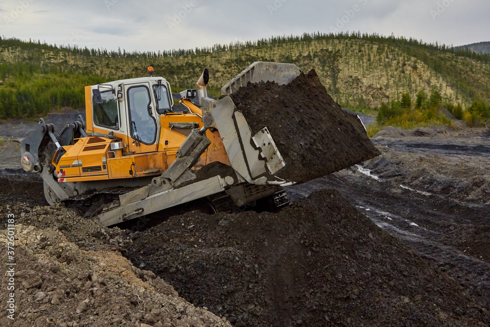 bulldozer is pushing the gold sands. Gold mining in Kolyma