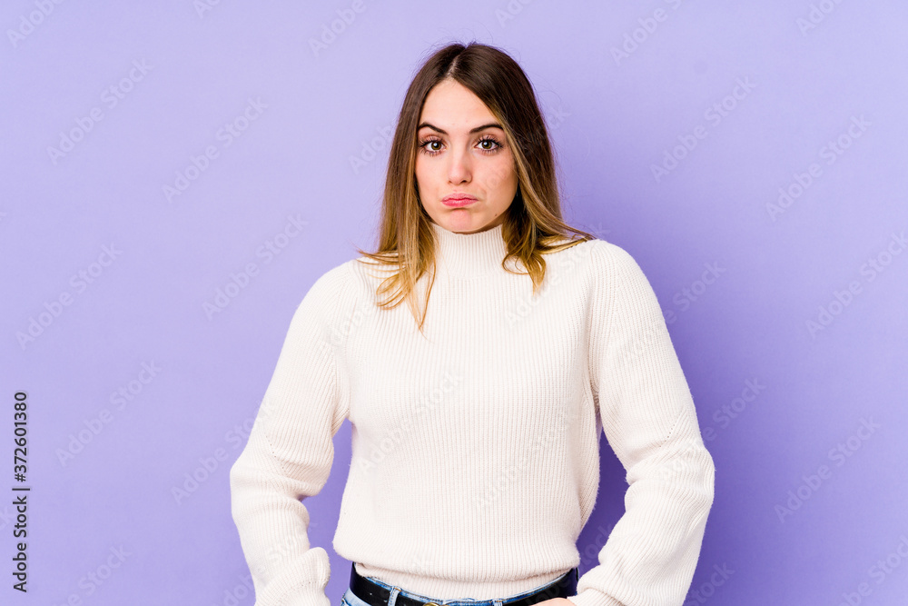 Young caucasian woman isolated on purple background blows cheeks, has tired expression. Facial expression concept. Young caucasian woman isolated on purple background blows cheeks, has tired expression. Facial expression concept.