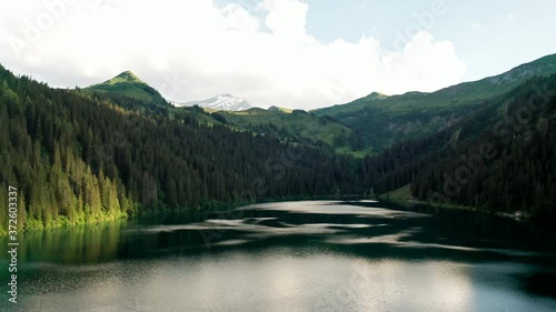Flying Down Low over Swiss Mountain Lake. Cinematic Drone View of Arnensee, Switzerland. Cloudy Winter Weather.  Rough Wild Mountain Look. photo