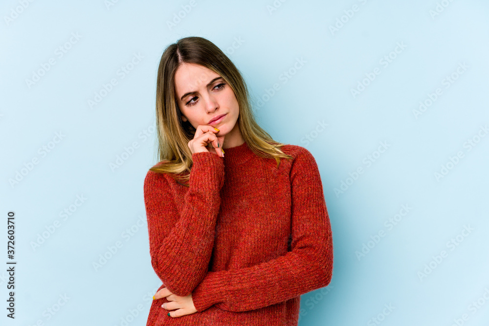 Young caucasian woman isolated on blue background looking sideways with doubtful and skeptical expression. Young caucasian woman isolated on blue background looking sideways with doubtful and skeptical expression.