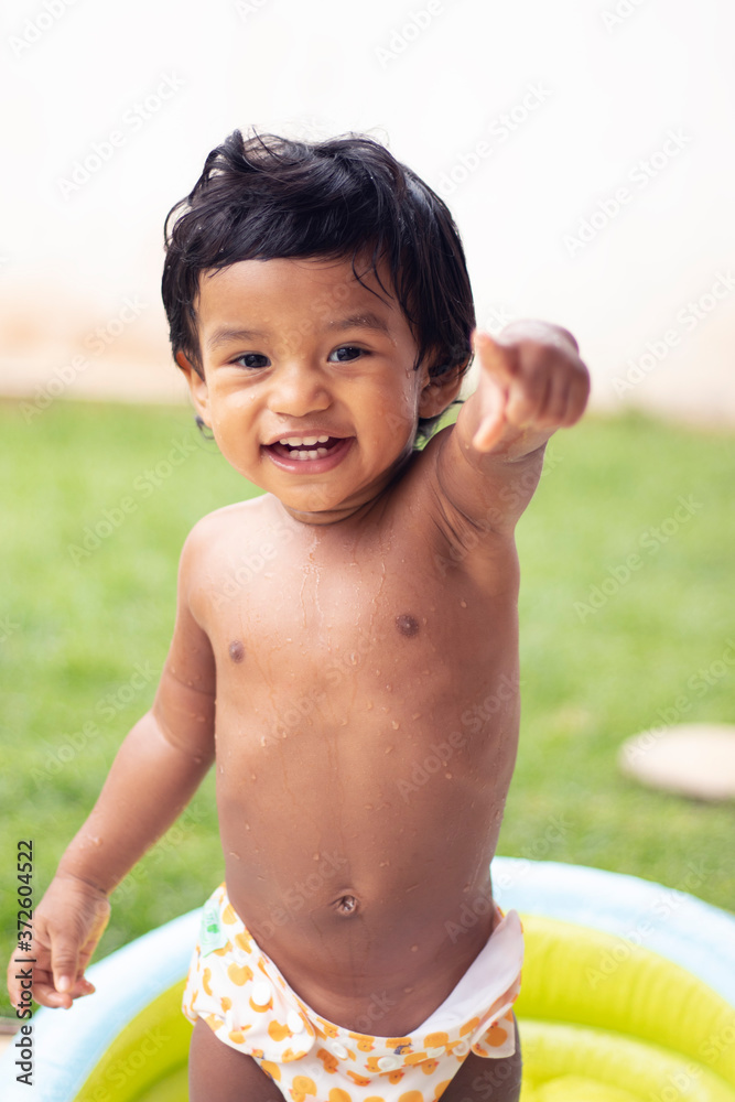 Funny little boy playing with water in baby flatable pool 