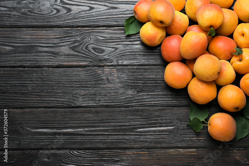 Many fresh ripe apricots on black wooden table  flat lay. Space for text