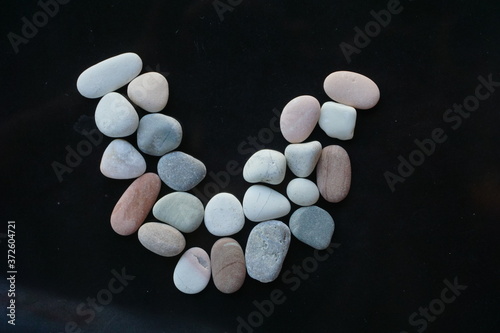 V letter shape of Pebble stones on dark background concepts. © muhammad