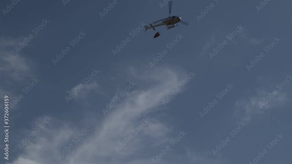 Helicopter flying to get some water with the bucket to extinguish the summer fire in Italy, Calabria.