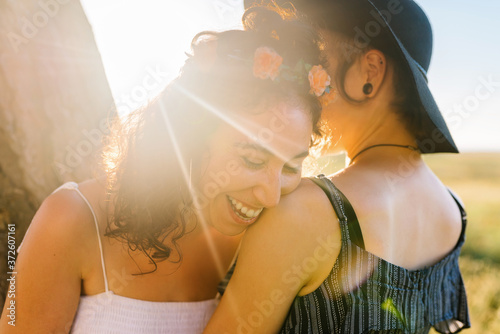 Delighted lesbian couple cuddling during sundown photo