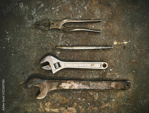 Top view set of various metal instruments for metalworking including wrenches and pliers arranged on grunge gray surface