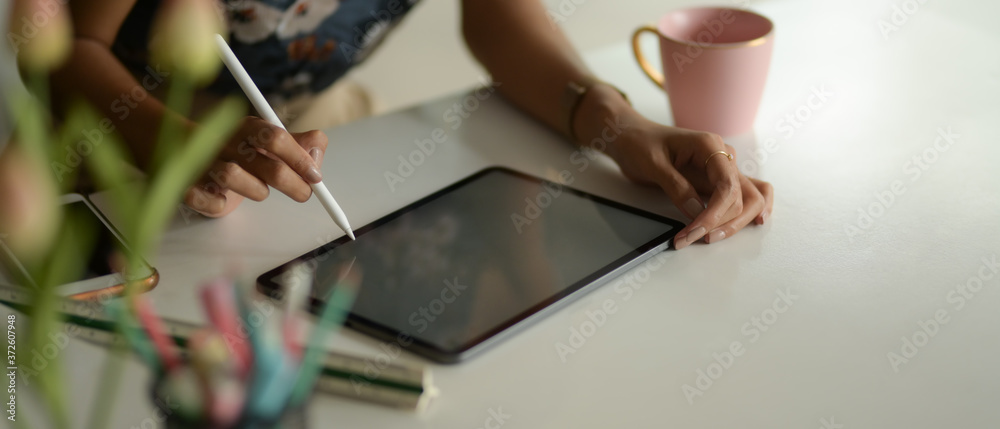 Close up view of female hands working with digital tablet on working table