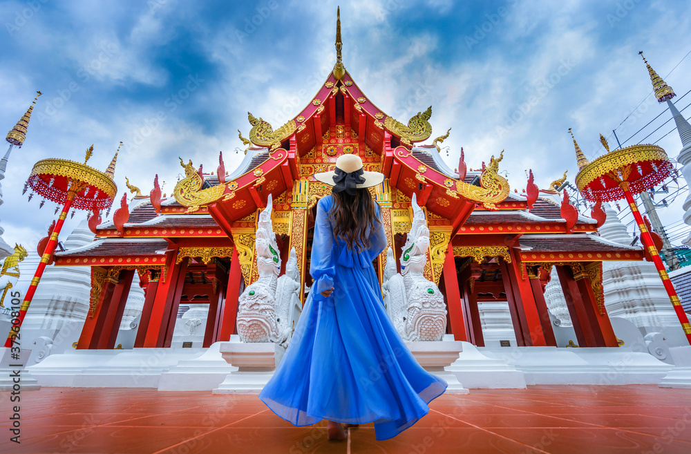 Fototapeta premium Asian female tourist wearing a blue dress visits Khuakrae Temple in Chiang Rai, Thailand.